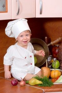 Small boy sitting on a counter wearing a chef's hat